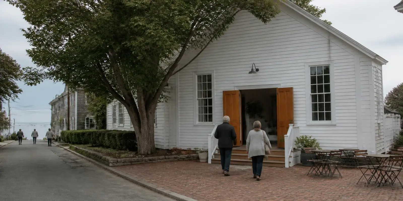 Harbor Light Church on a Sunday morning: a white clapboard building with open doors and a brick courtyard under a shade tree